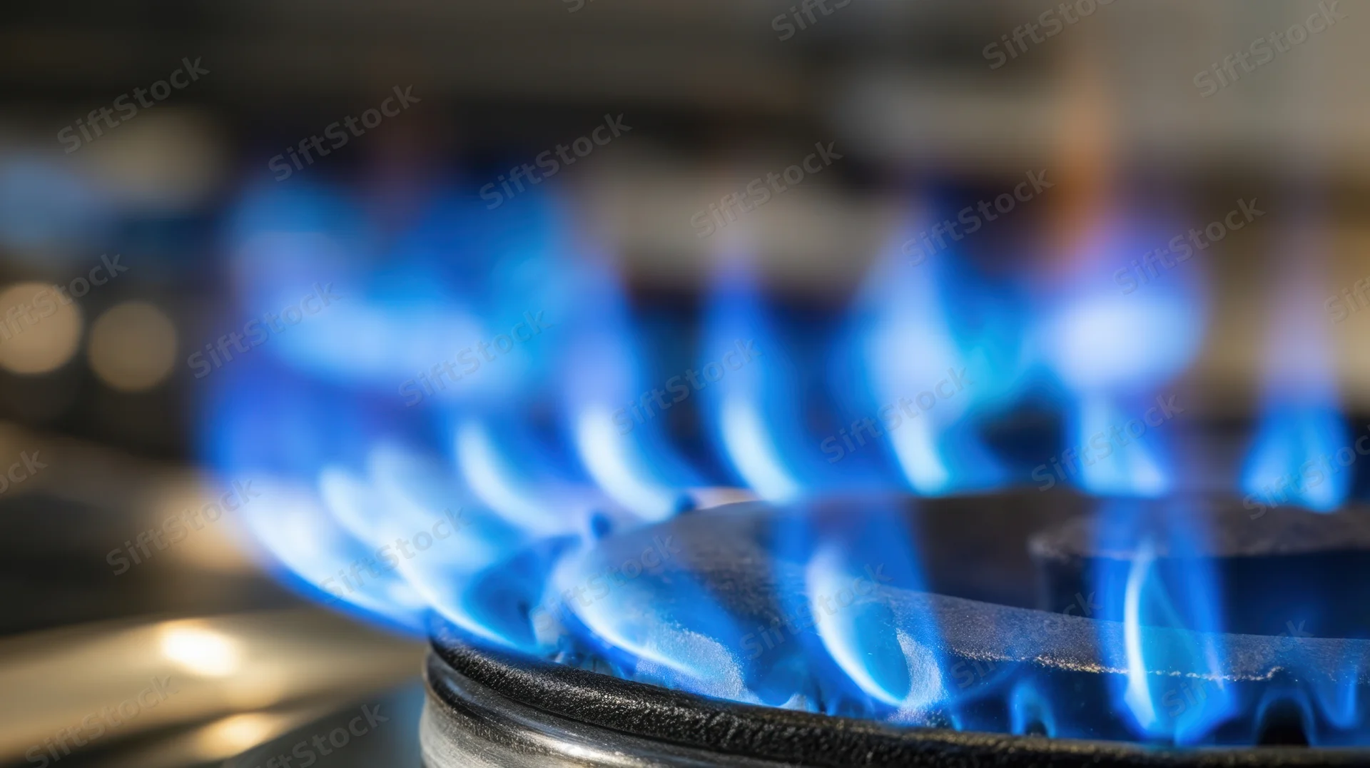 Blue flames burning on a gas stove burner in a kitchen