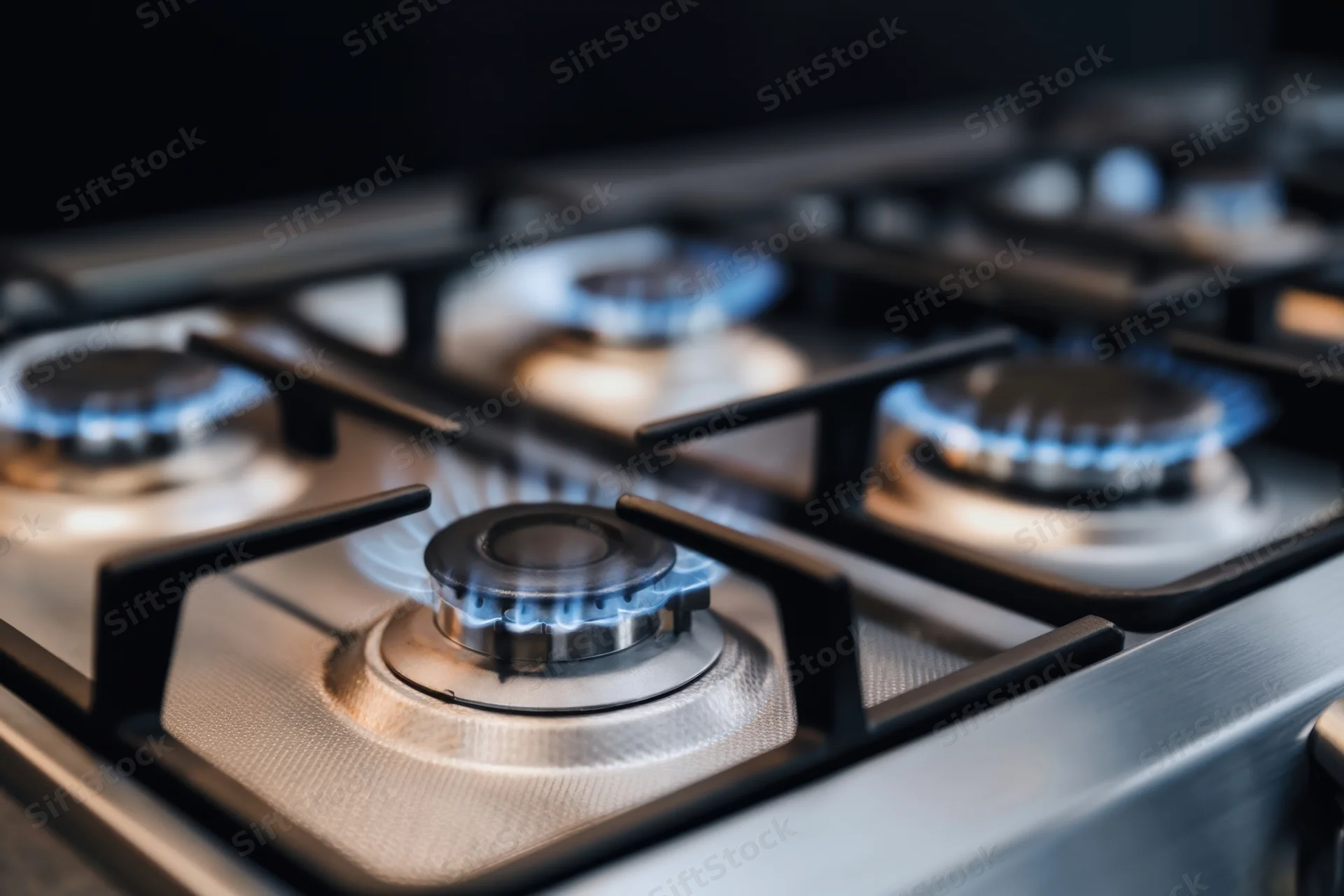 Close-up of lit gas burners on a stainless steel cooktop in a kitchen