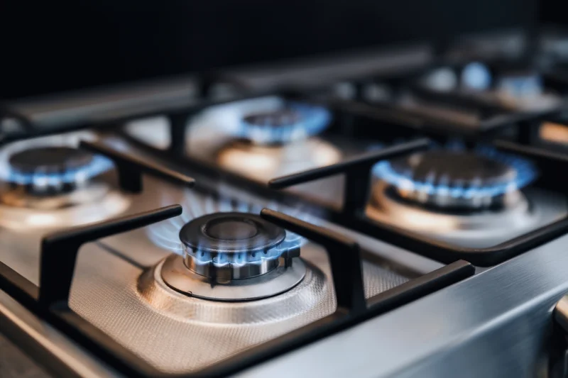 Close-up of lit gas burners on a stainless steel cooktop in a kitchen