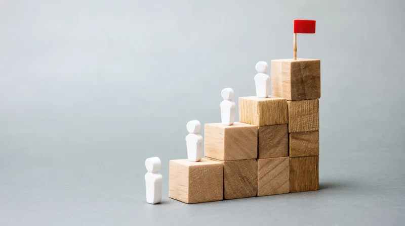 White figures ascending wooden blocks toward a red flag at the top
