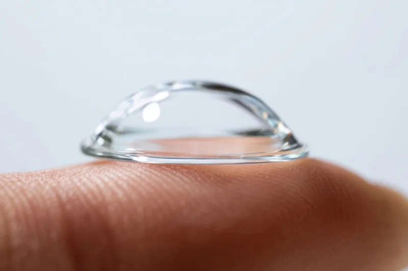 Contact lens resting on a fingertip against a plain white background
