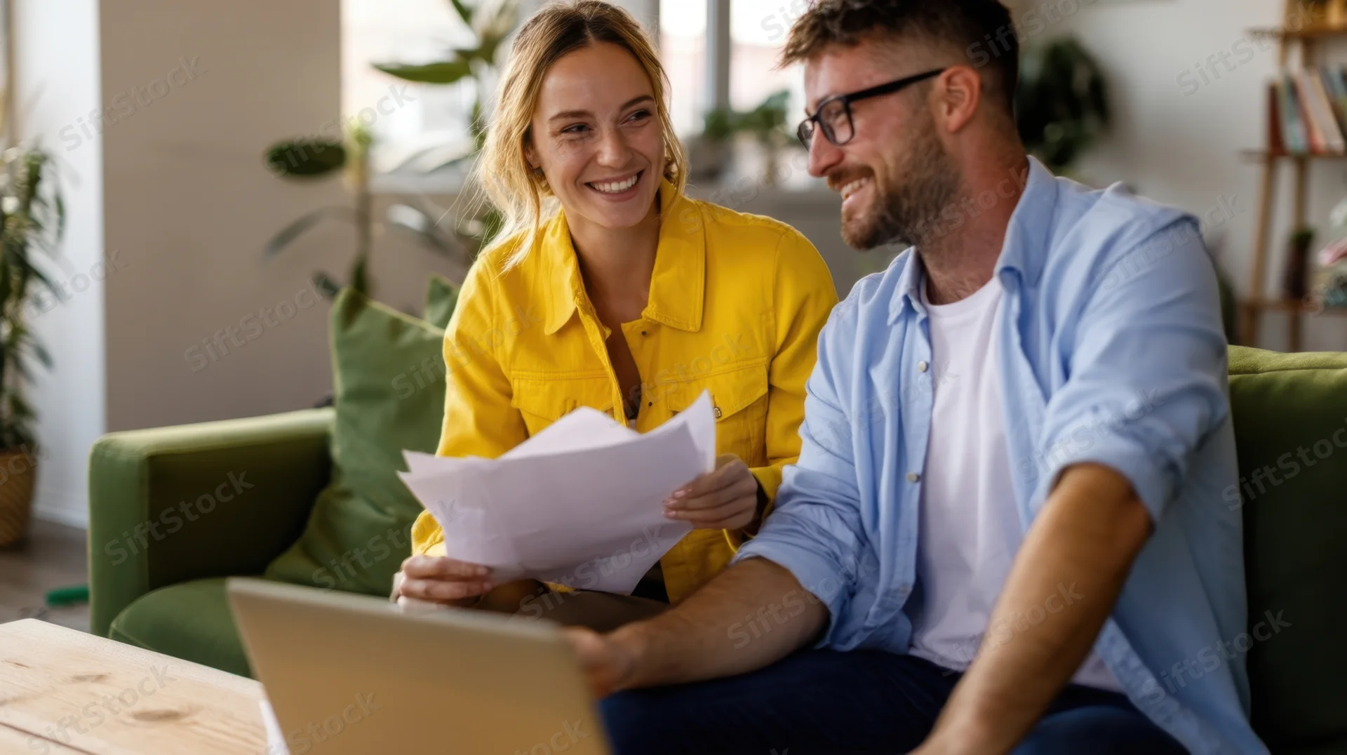 Couple smiling while discussing papers on a couch in a living room