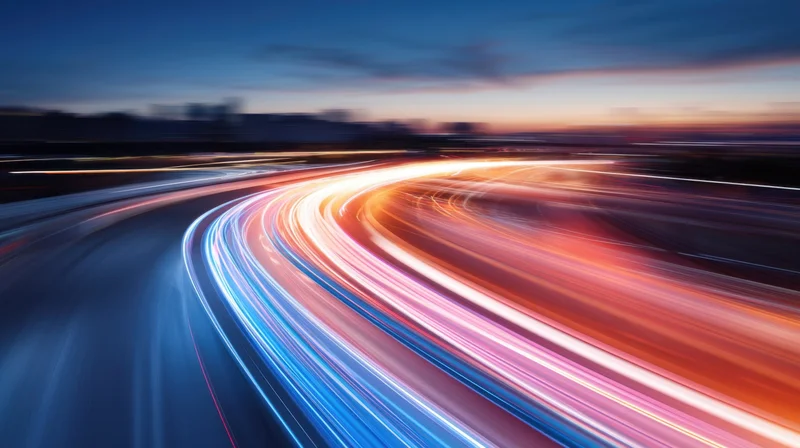 Curved highway at dusk with light trails from moving vehicles