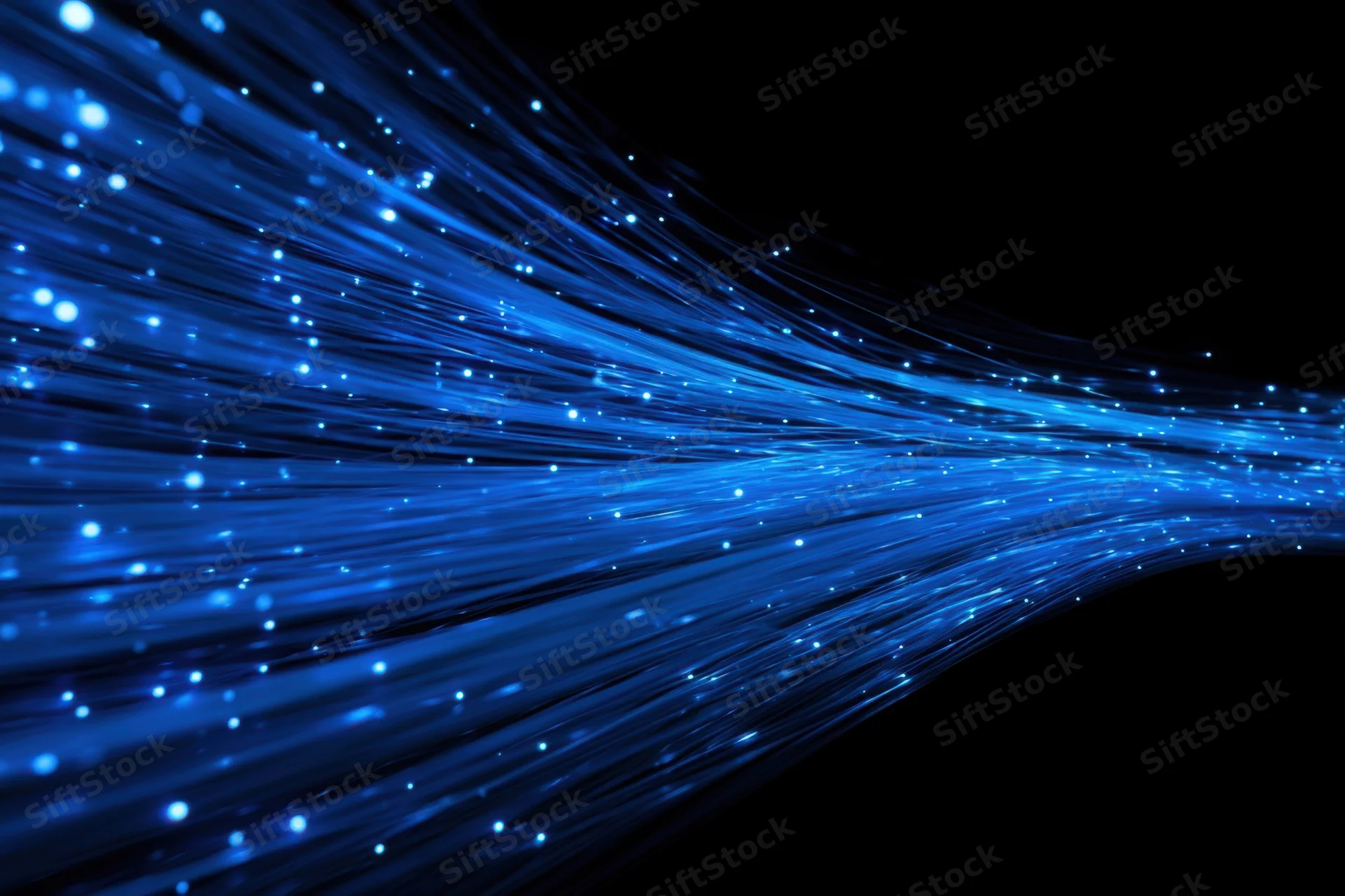 Glowing blue fiber optic cables flowing against dark background