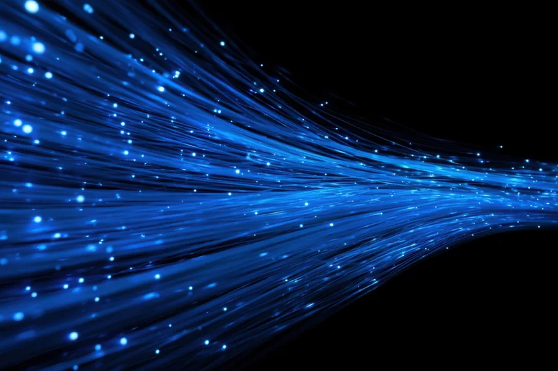 Glowing blue fiber optic cables flowing against dark background