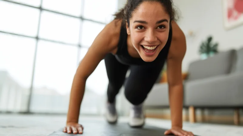 Woman doing pushup on exercise mat in living room smiling at camera