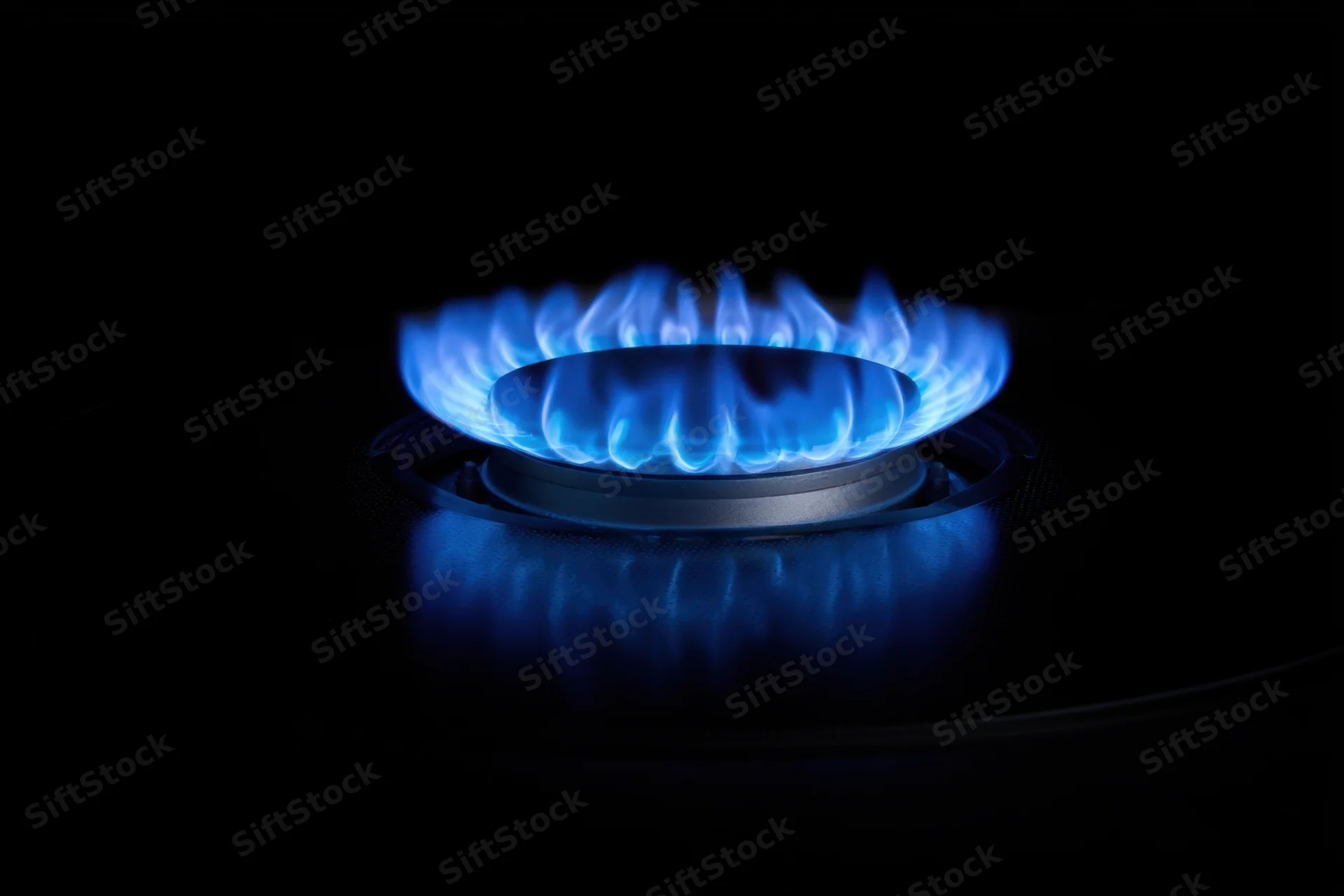 Blue flame burning on a gas stove burner in a dark setting