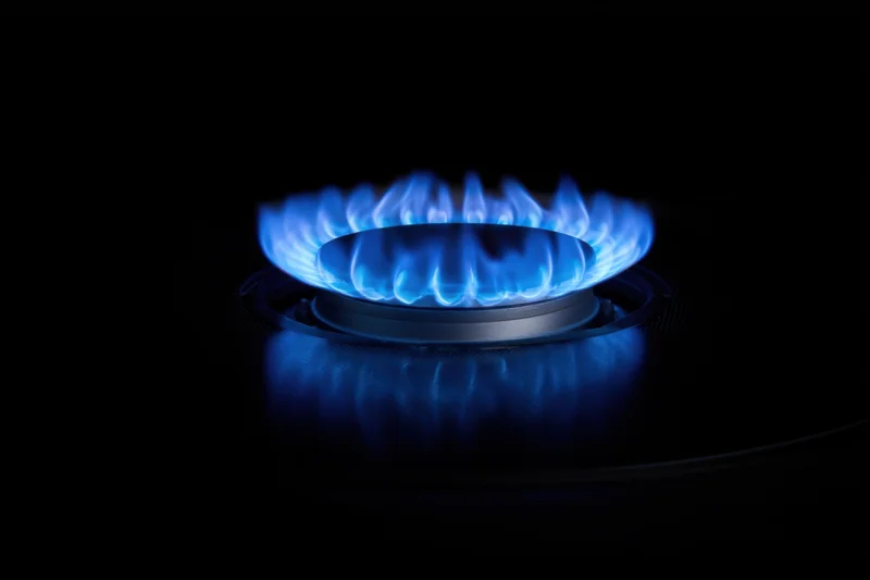 Blue flame burning on a gas stove burner in a dark setting