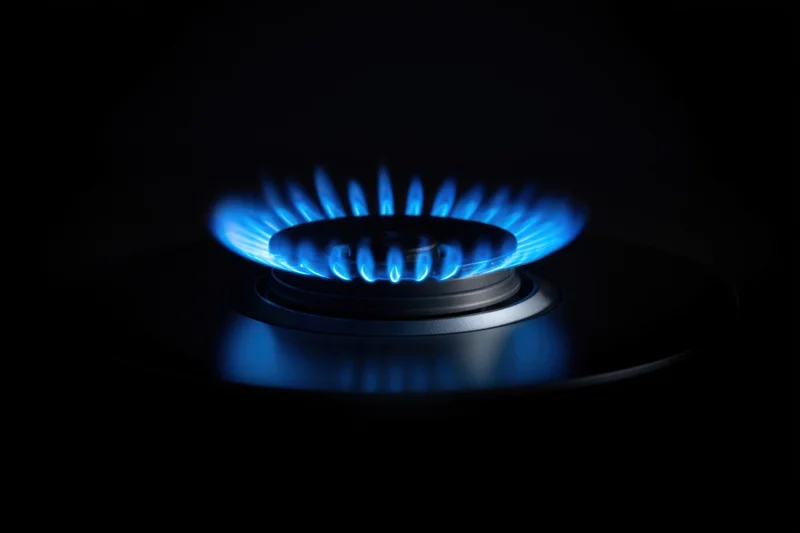 Blue flame burning on a gas stove burner in darkness