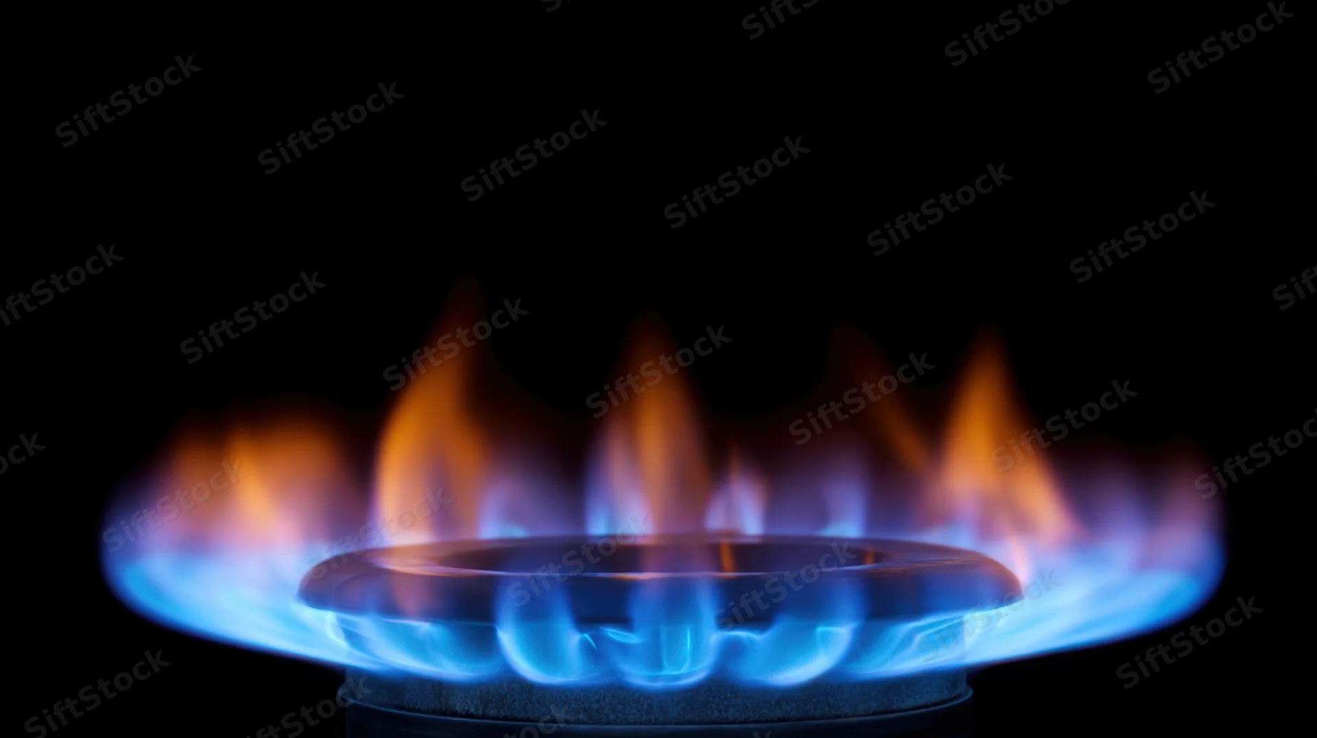 Blue flame burning on a gas stove burner against black background