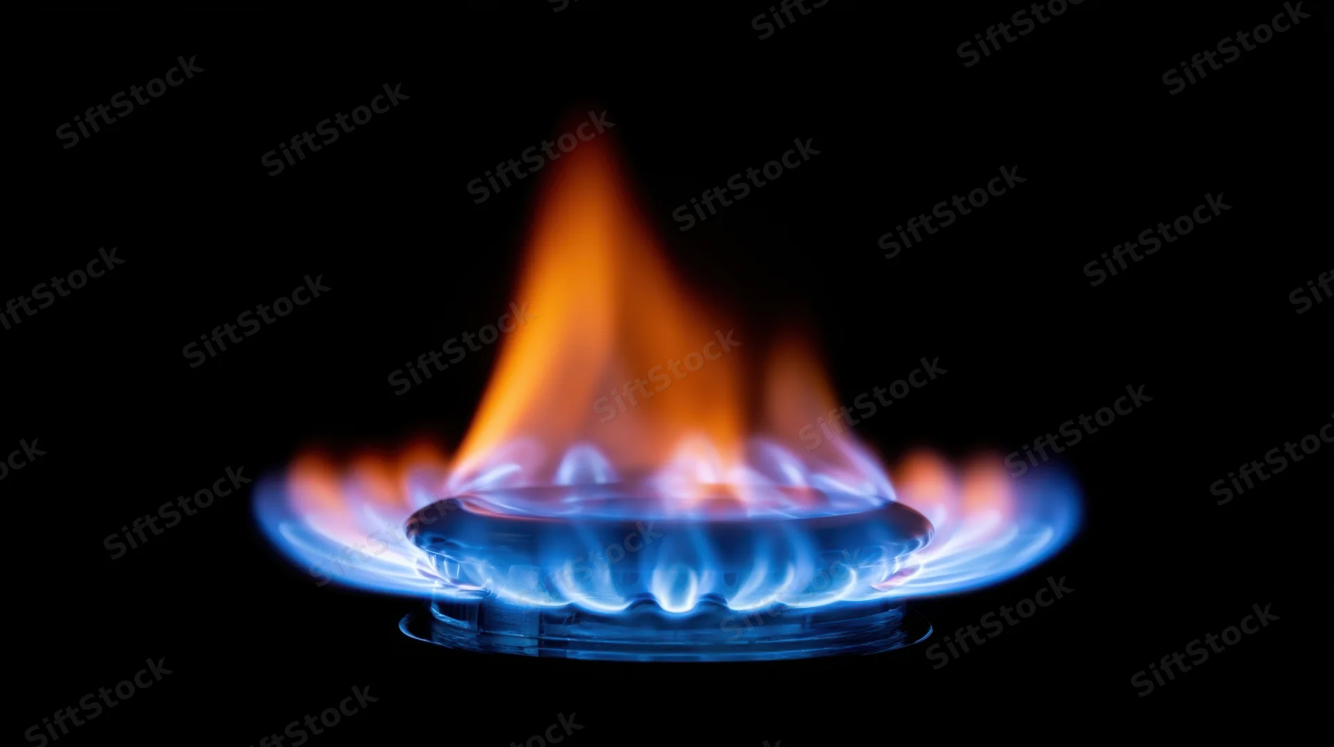 Blue and orange flame burning on a gas stove burner against black background