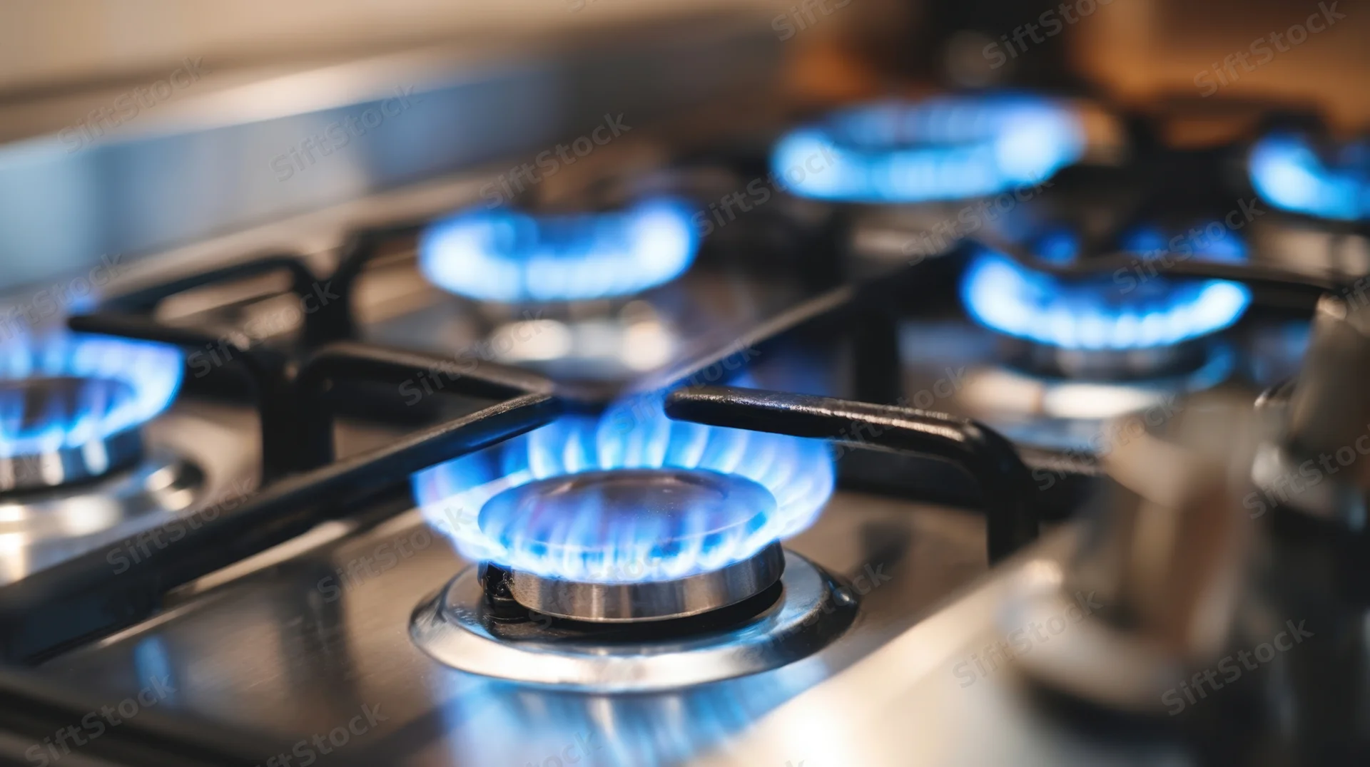 Close-up of lit gas burners on a stainless steel stove in a kitchen