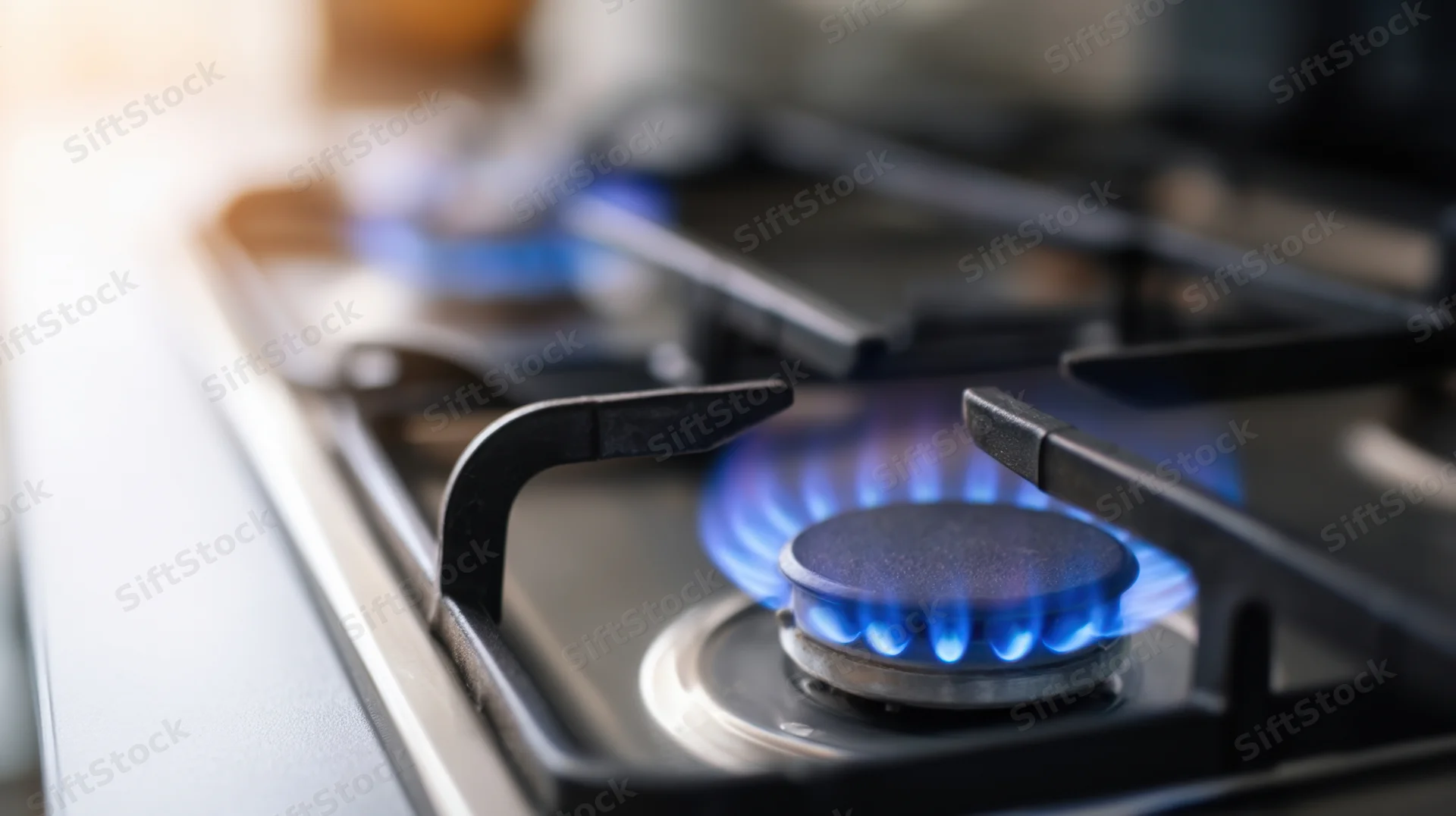 Close-up of a lit gas stove burner with blue flame in a kitchen setting