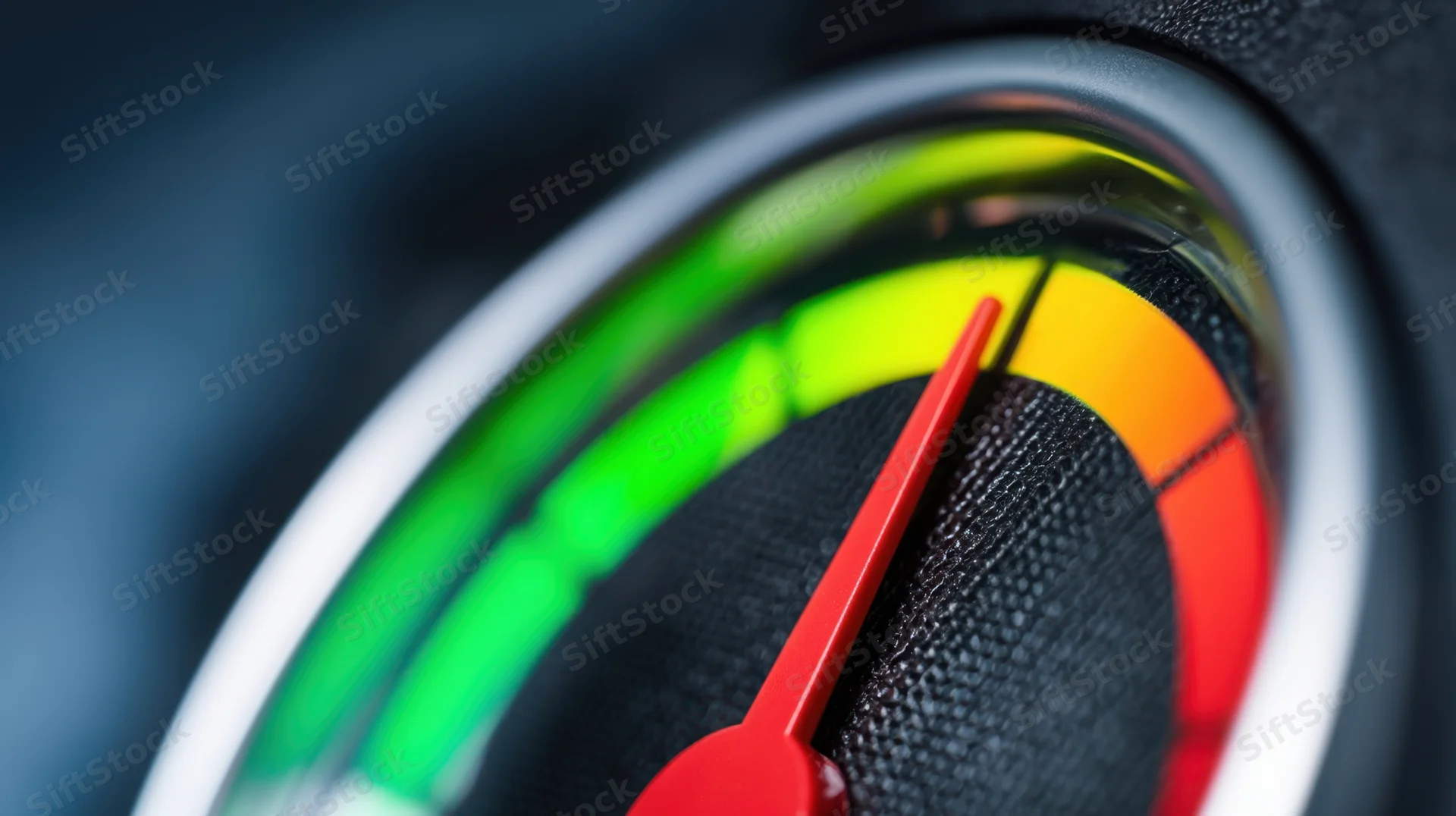 Close-up of a red needle on a circular gauge with color-coded segments in a vehicle dashboard