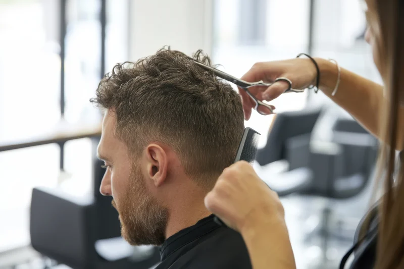 Man receiving haircut with scissors and comb in salon