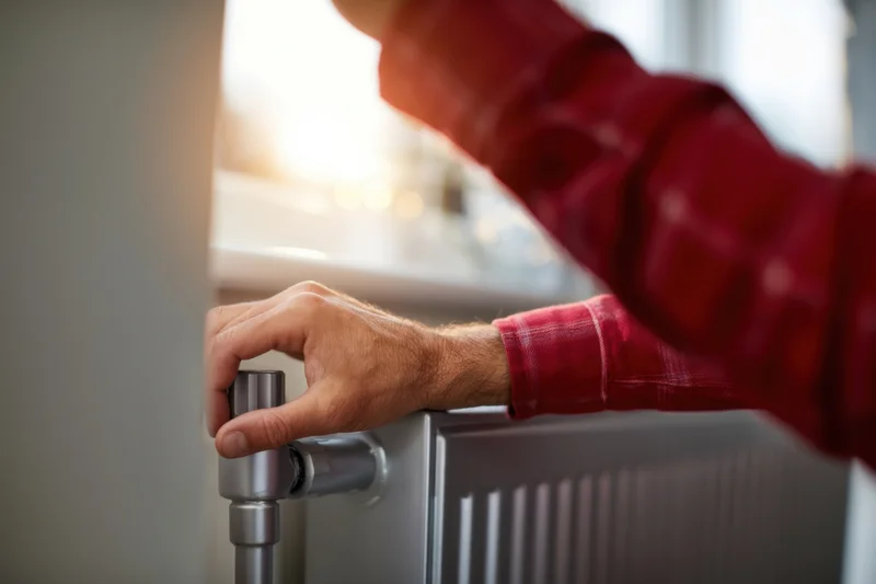 Hand adjusting radiator valve in a home interior