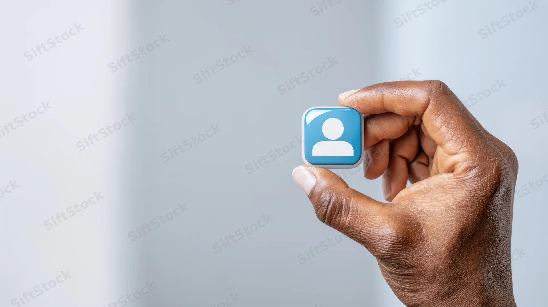 Hand holding a blue user profile icon against a light background