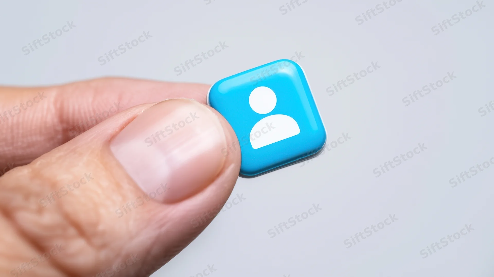 Hand holding a blue user profile icon against a light background