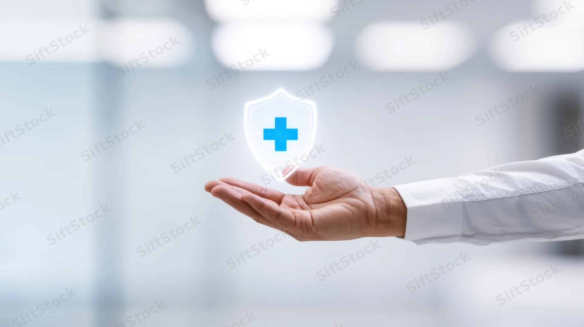Hand holding a glowing medical shield symbol in an office setting