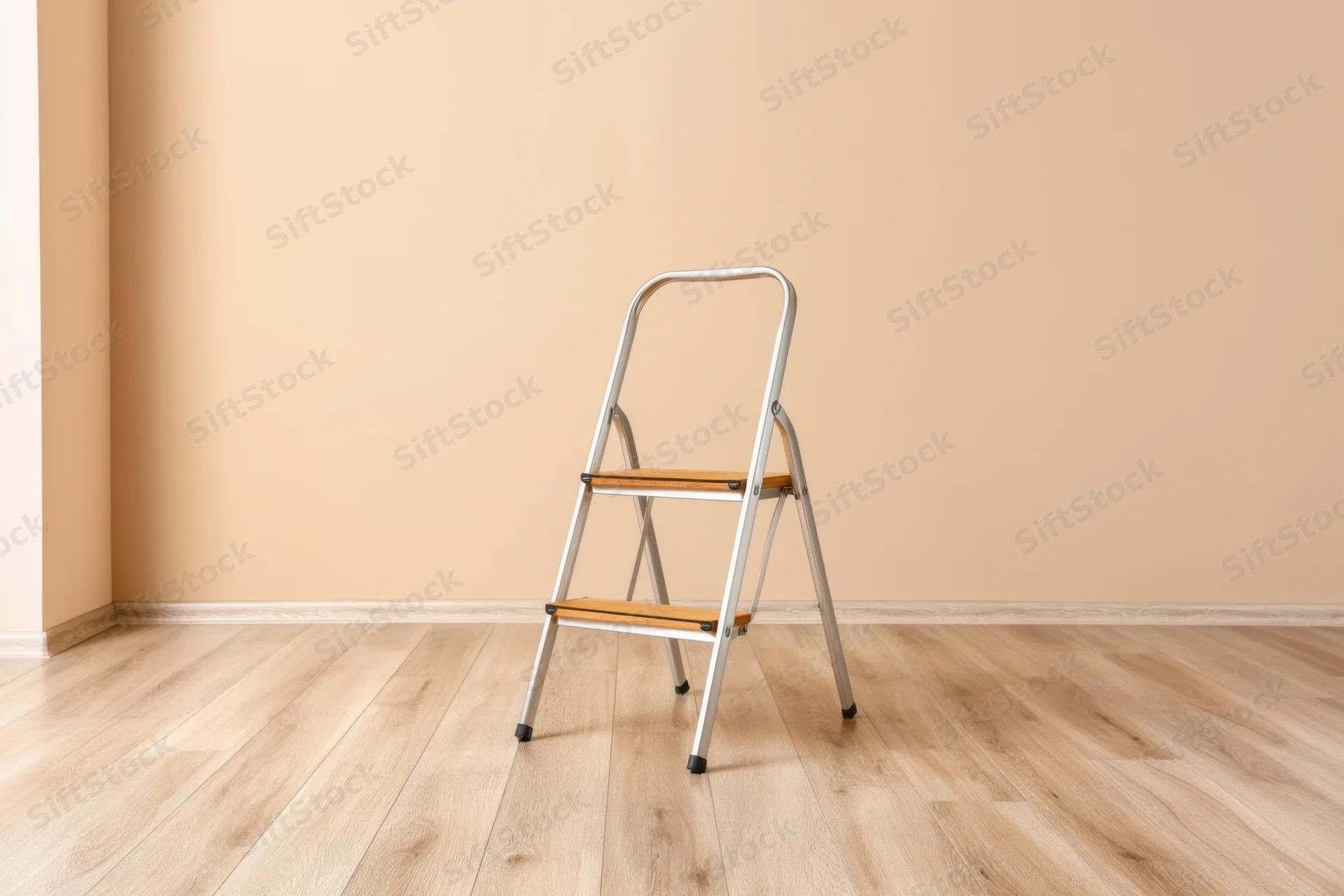 Folding stepstool with wooden steps and metal frame standing in an empty room with beige walls and laminate flooring