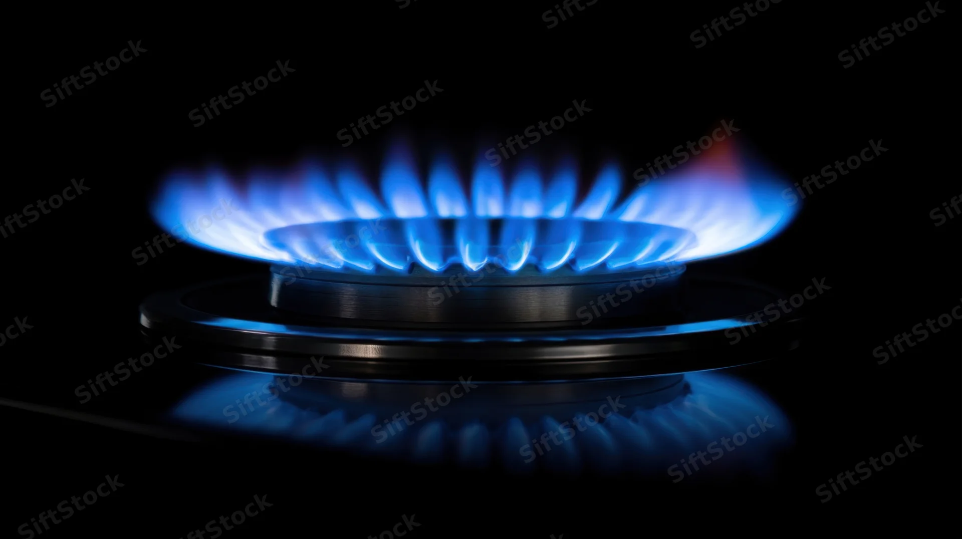 Blue flame burning on a gas stove burner in a dark setting