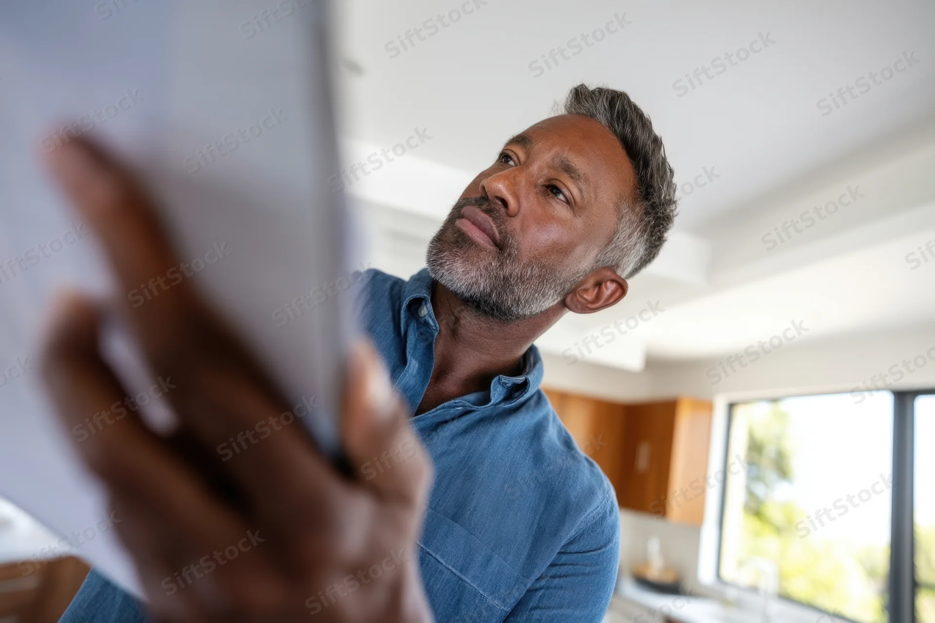 Man holding tablet while concentrating in modern kitchen interior