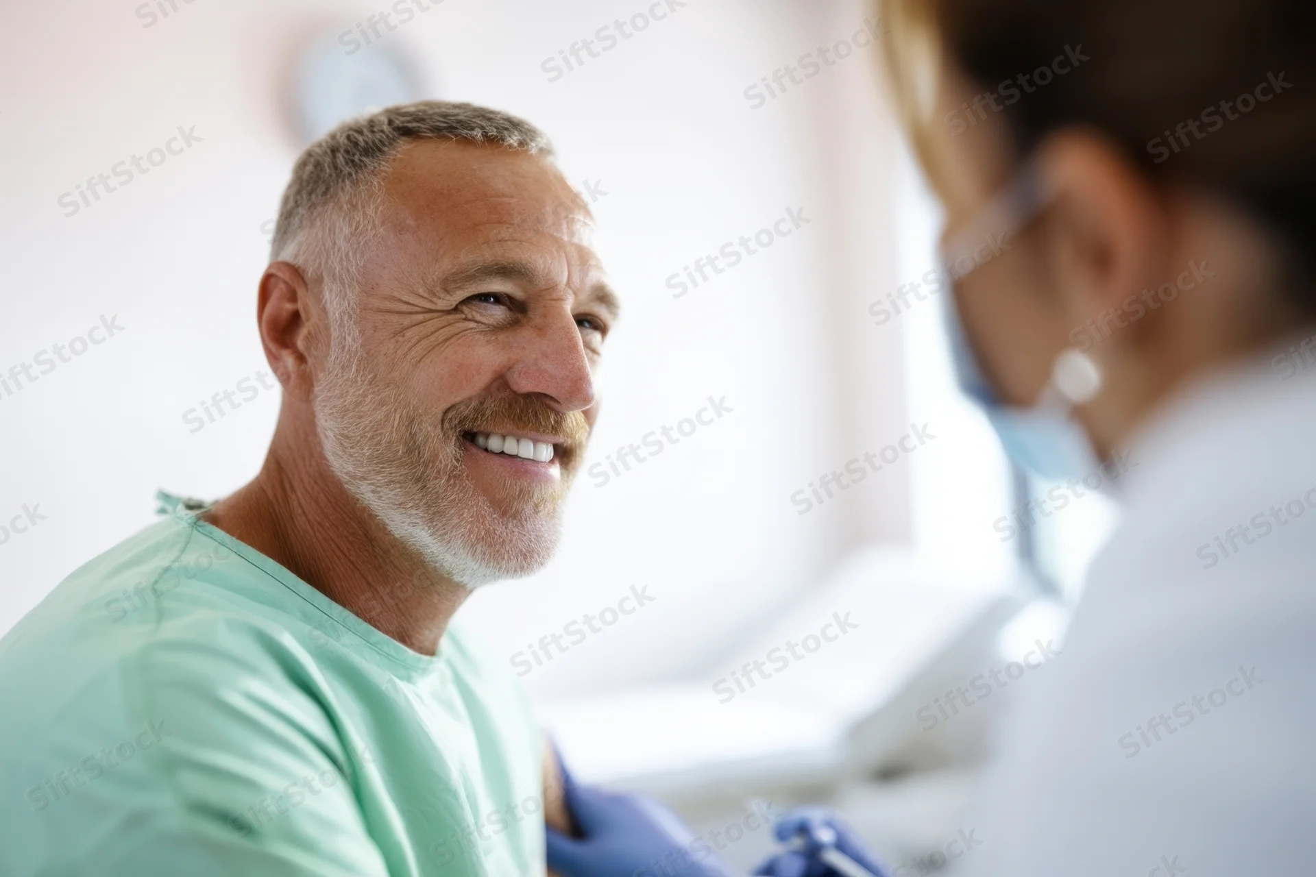 Smiling man in dental clinic during examination by female dentist