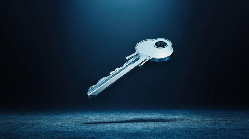 Metallic key floating in dark space under spotlight, casting shadow on textured surface