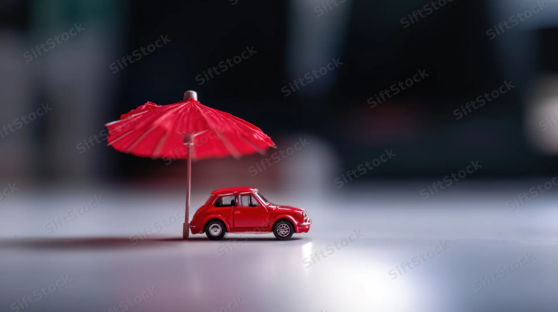 Red toy car under a small red umbrella on a smooth surface