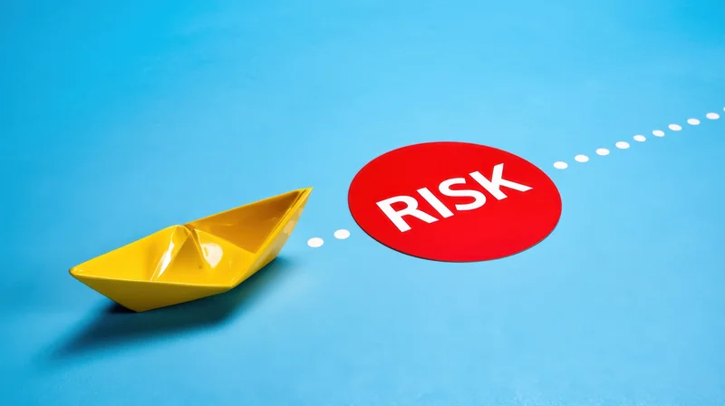 Yellow paper boat on blue surface approaching red circle labeled risk along dotted path