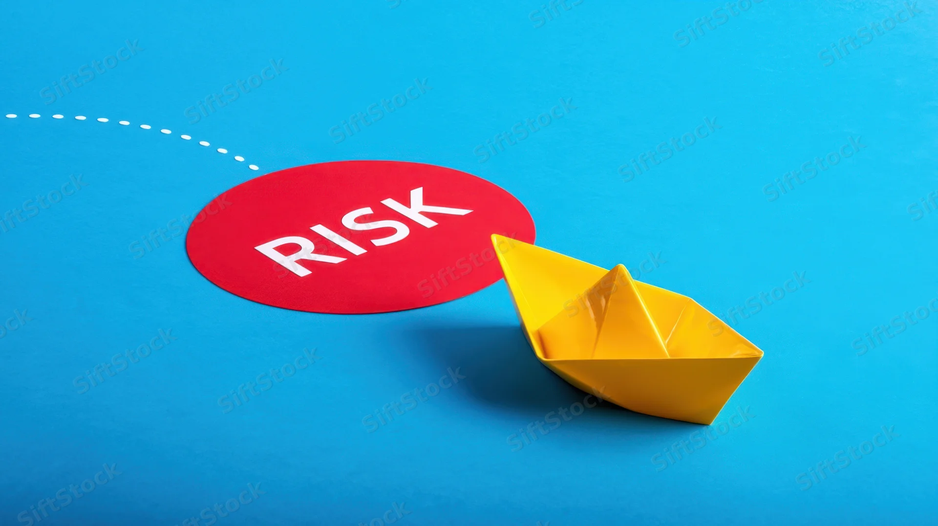 Yellow paper boat near red circle labeled risk on blue surface with dotted line path