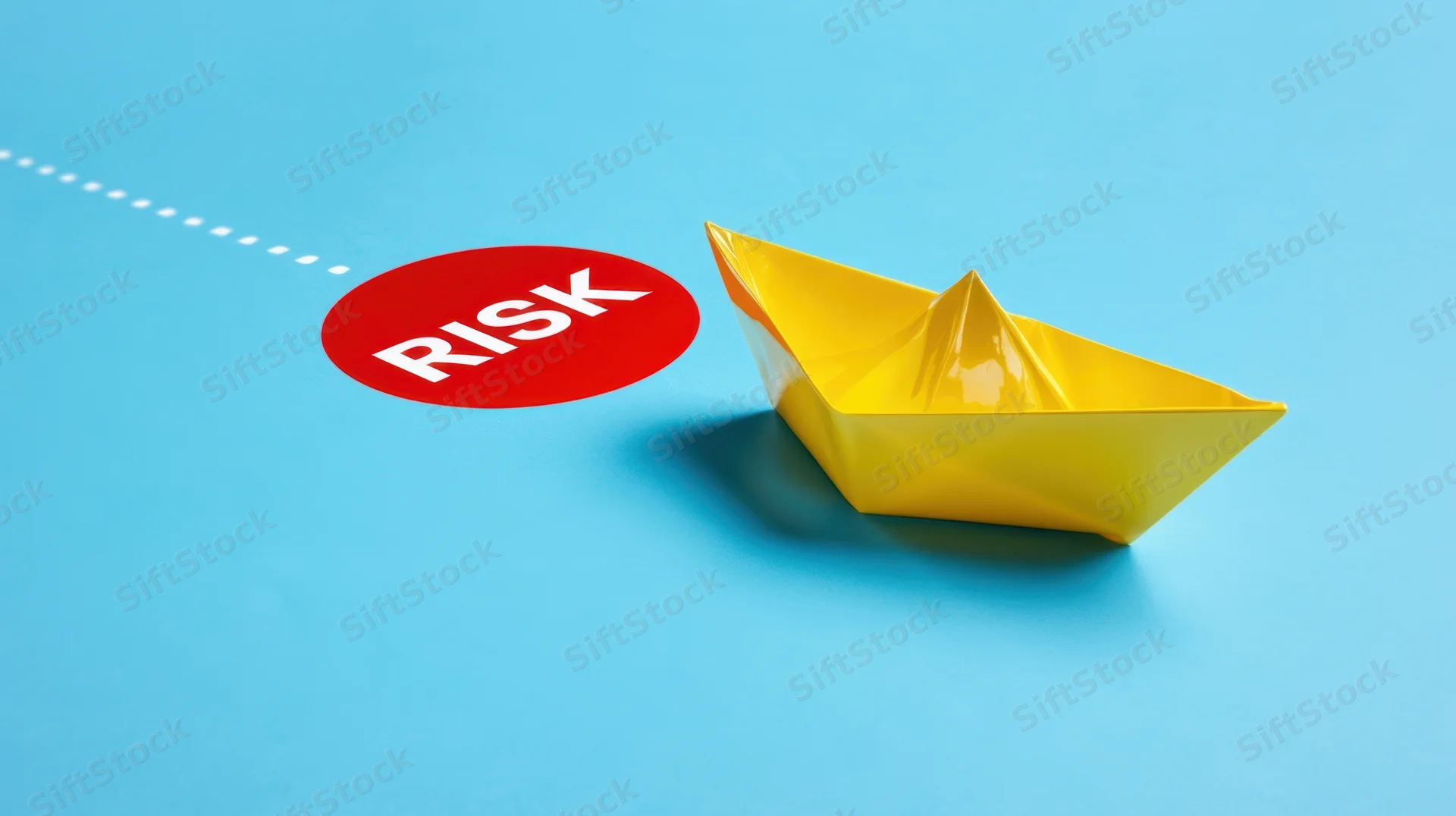 Yellow paper boat near red risk circle on blue surface with dotted line path