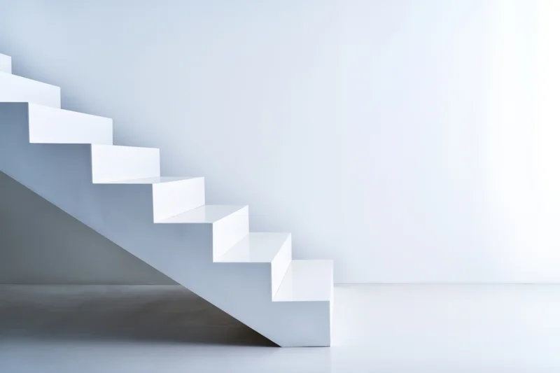 White minimalist staircase ascending in a bright empty interior space