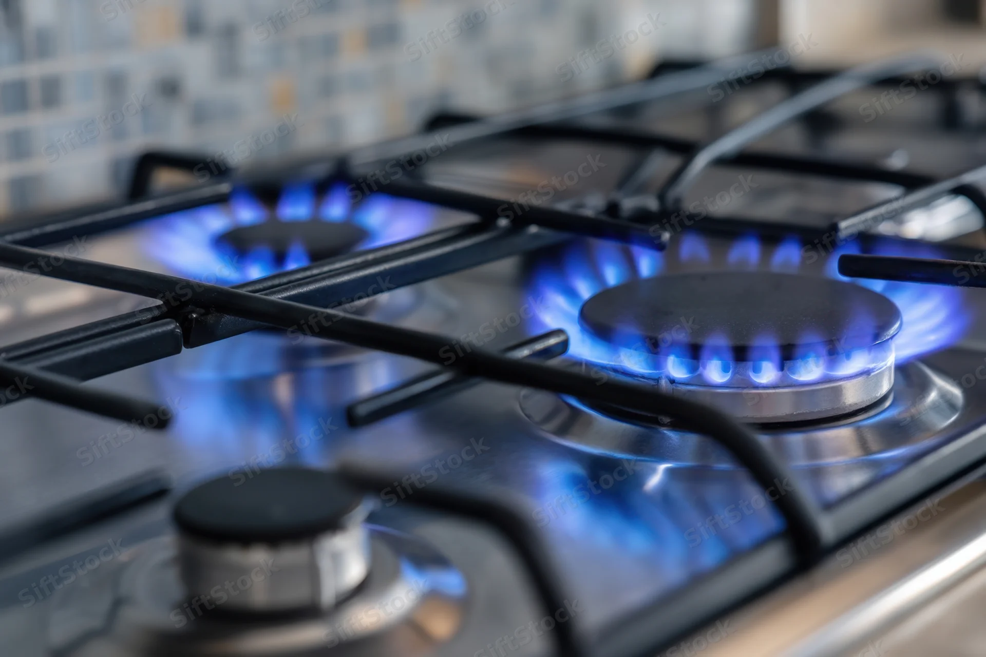 Close-up of lit gas burners on a stainless steel cooktop in a modern kitchen