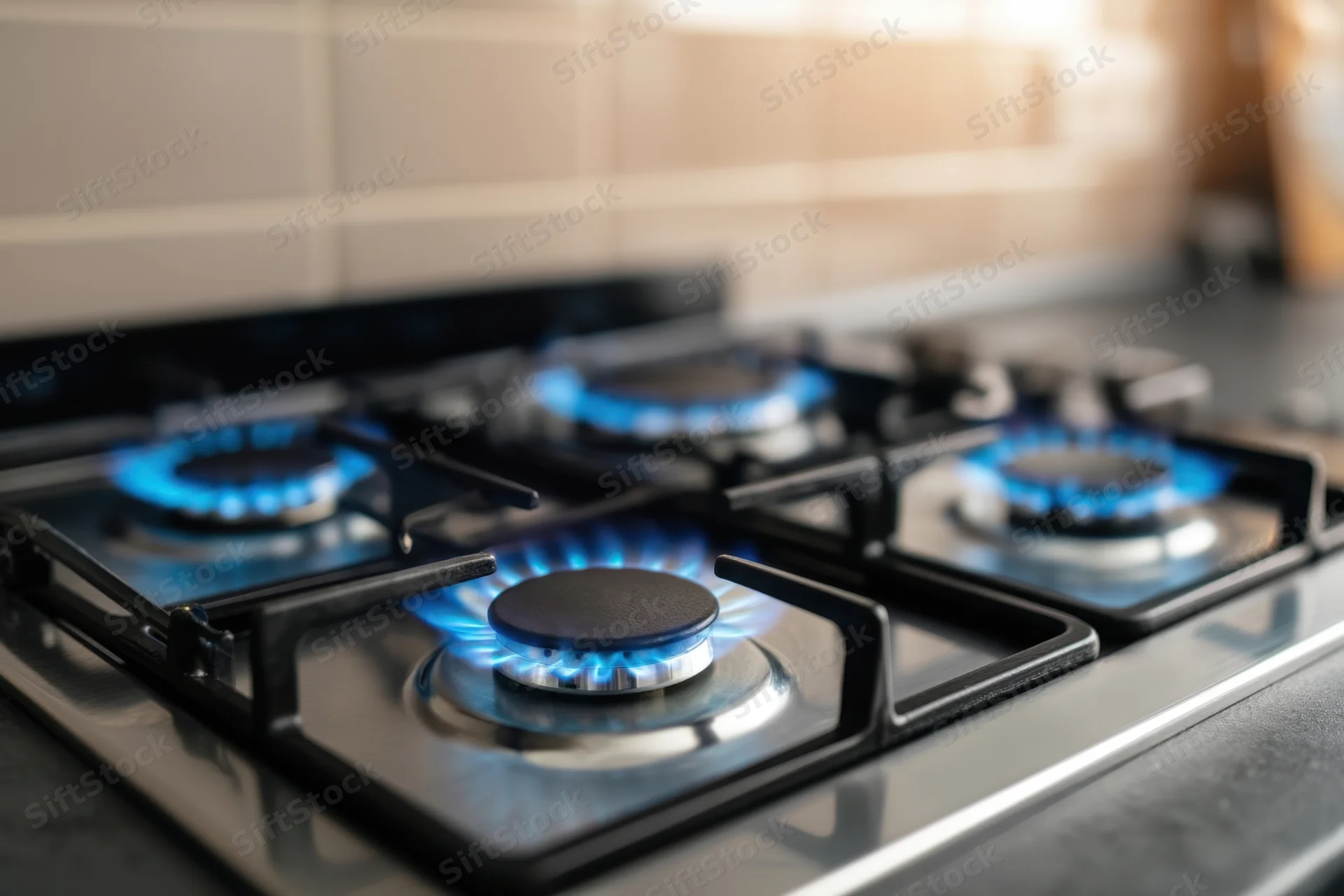 Modern gas stove with blue flames burning on stainless steel cooktop in kitchen