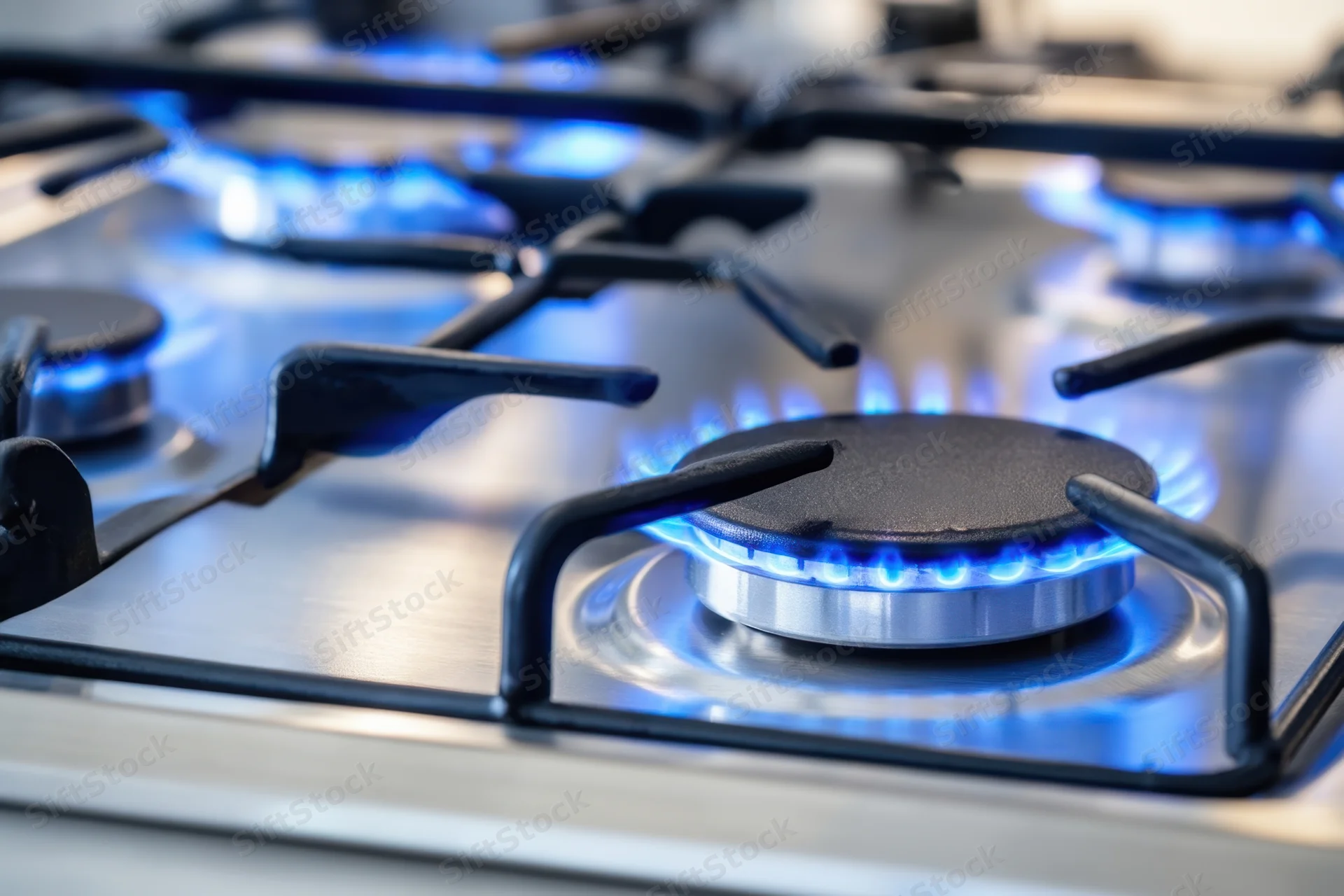 Closeup of blue flames burning on a modern stainless steel gas stove cooktop