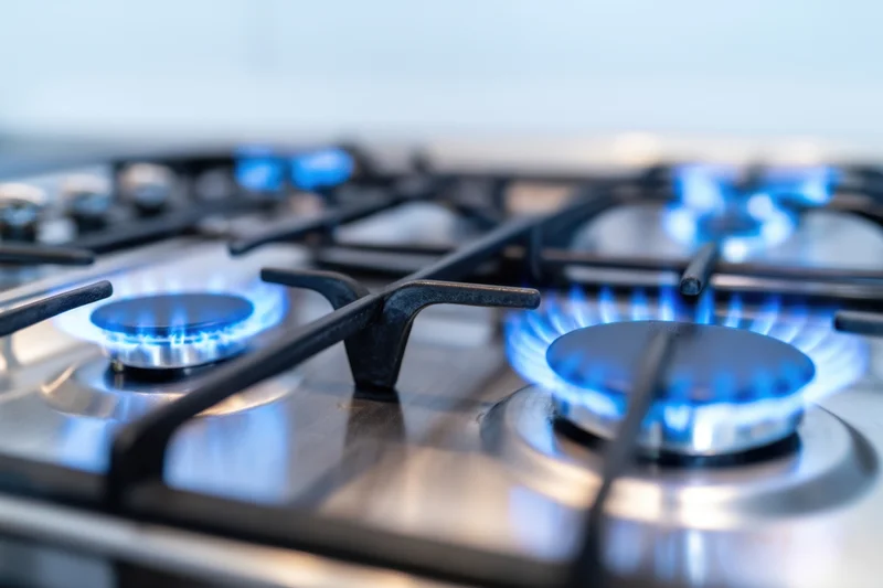Close-up of lit gas burners on a stainless steel cooktop in a modern kitchen