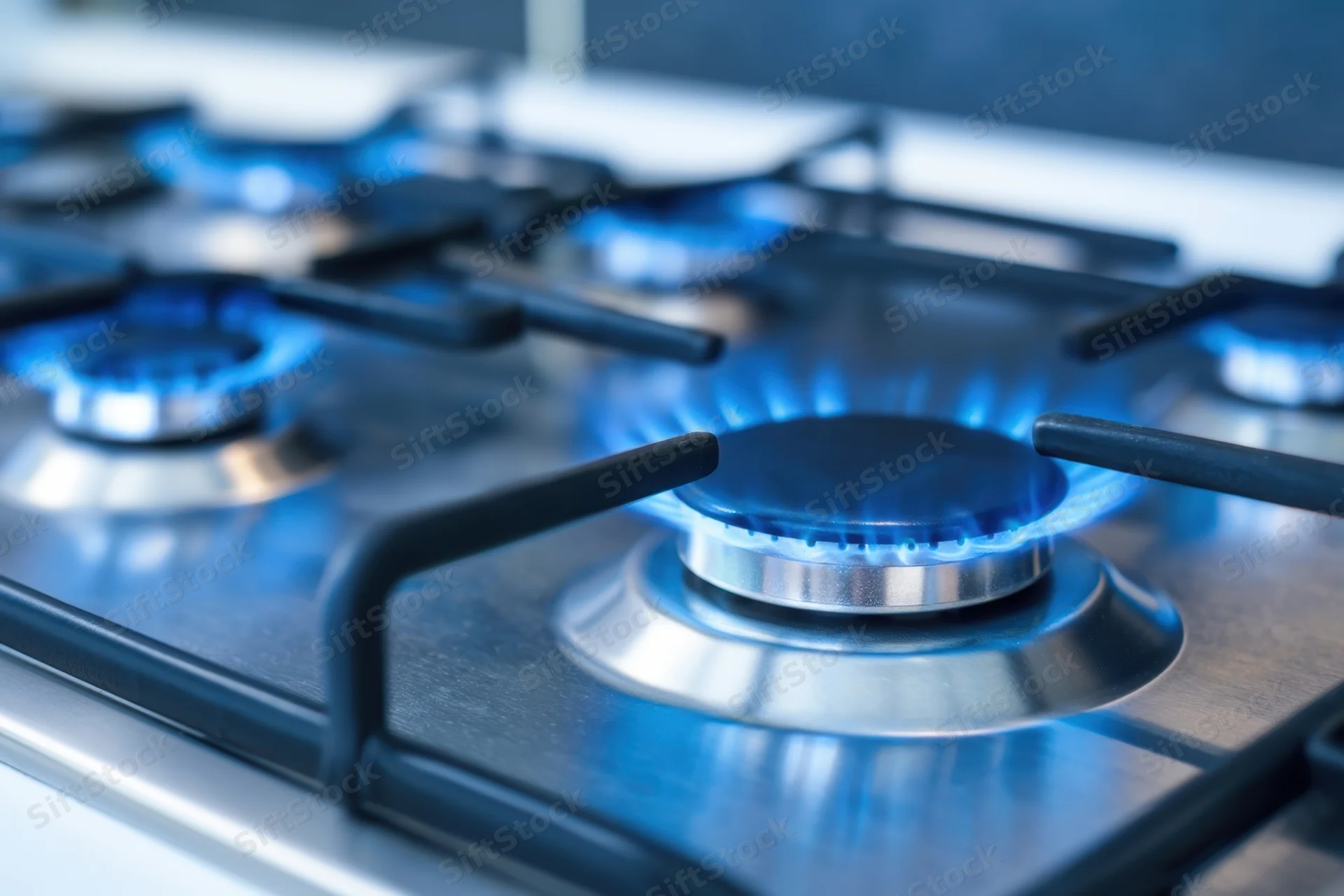 Close-up of lit gas burners on a stainless steel cooktop in a modern kitchen