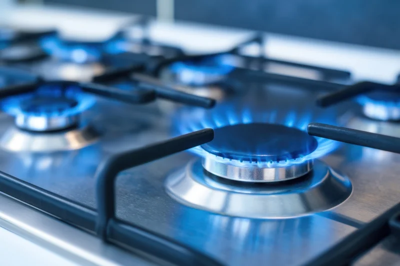 Close-up of lit gas burners on a stainless steel cooktop in a modern kitchen