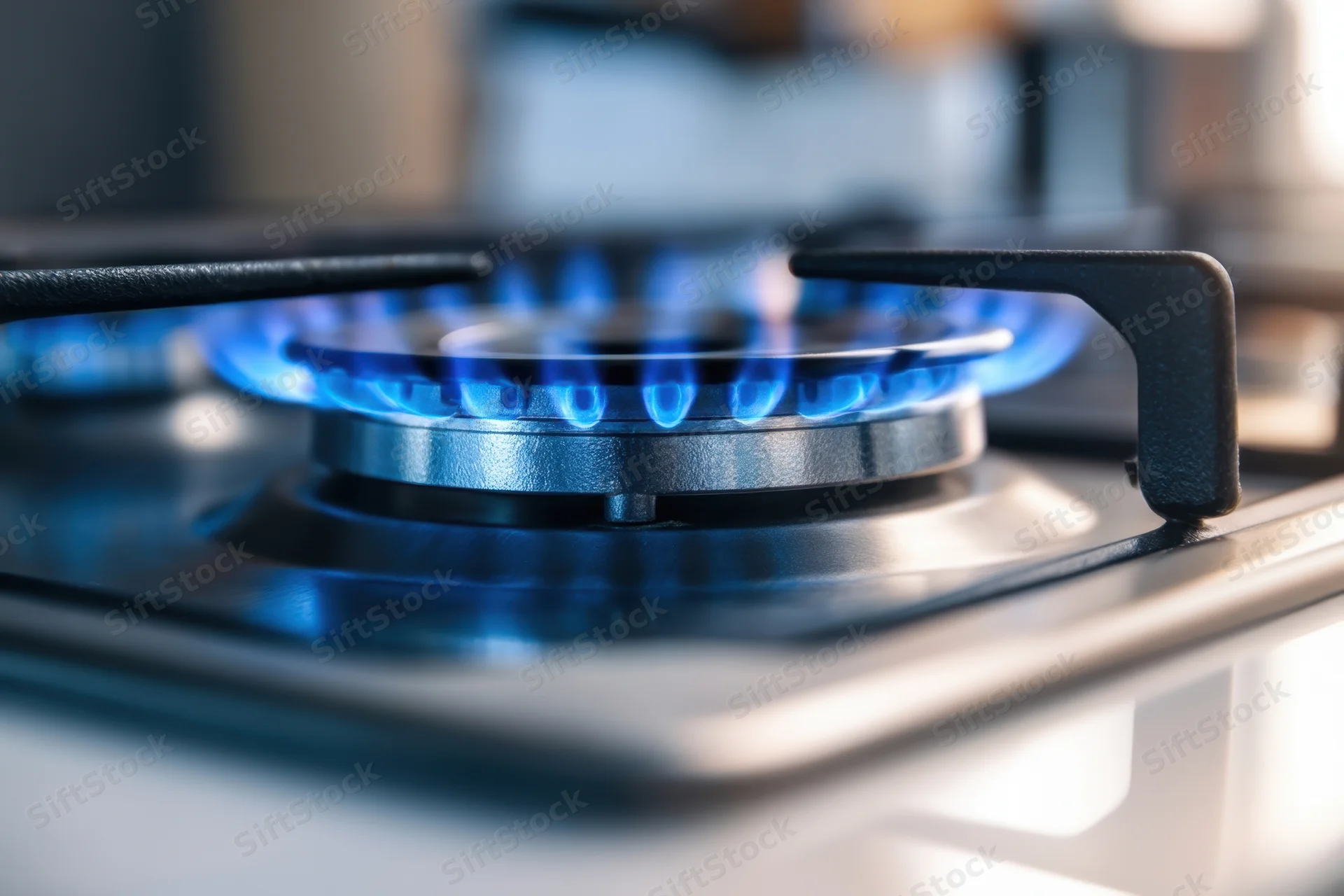 Close-up of a lit gas stove burner with blue flame on a modern cooktop