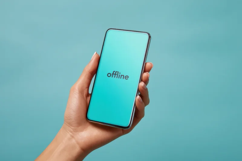 Hand holding smartphone with offline message on screen against teal background