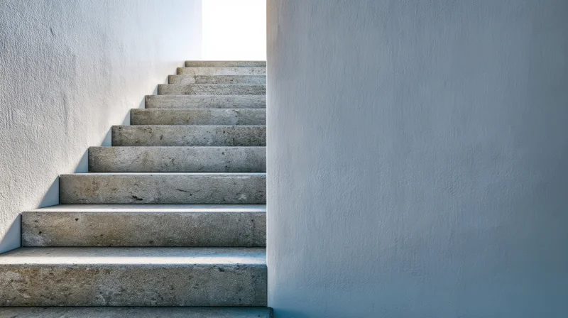 Concrete staircase ascending between white walls in a modern interior