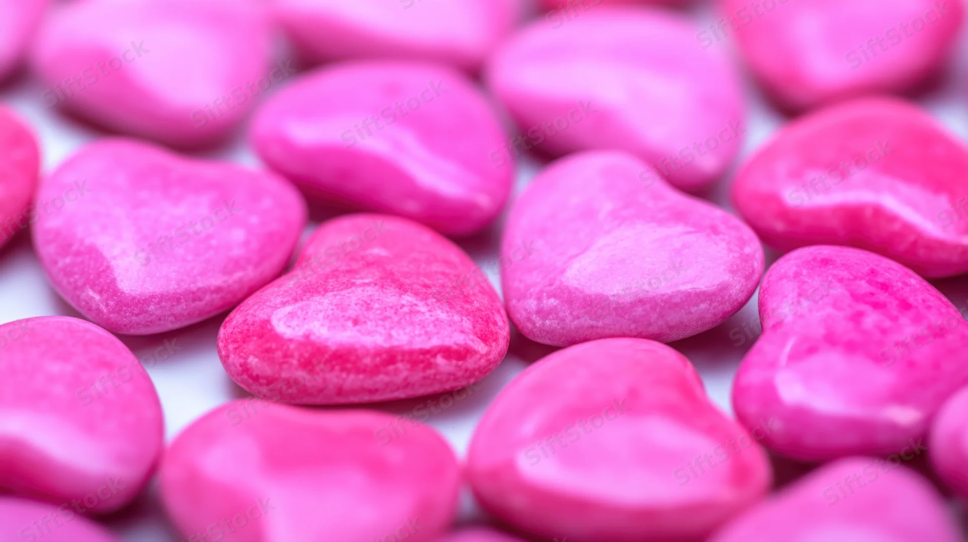 Pink heart-shaped candies scattered in close-up view