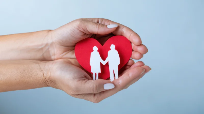 Hands holding a red heart with white couple cutout against light blue background