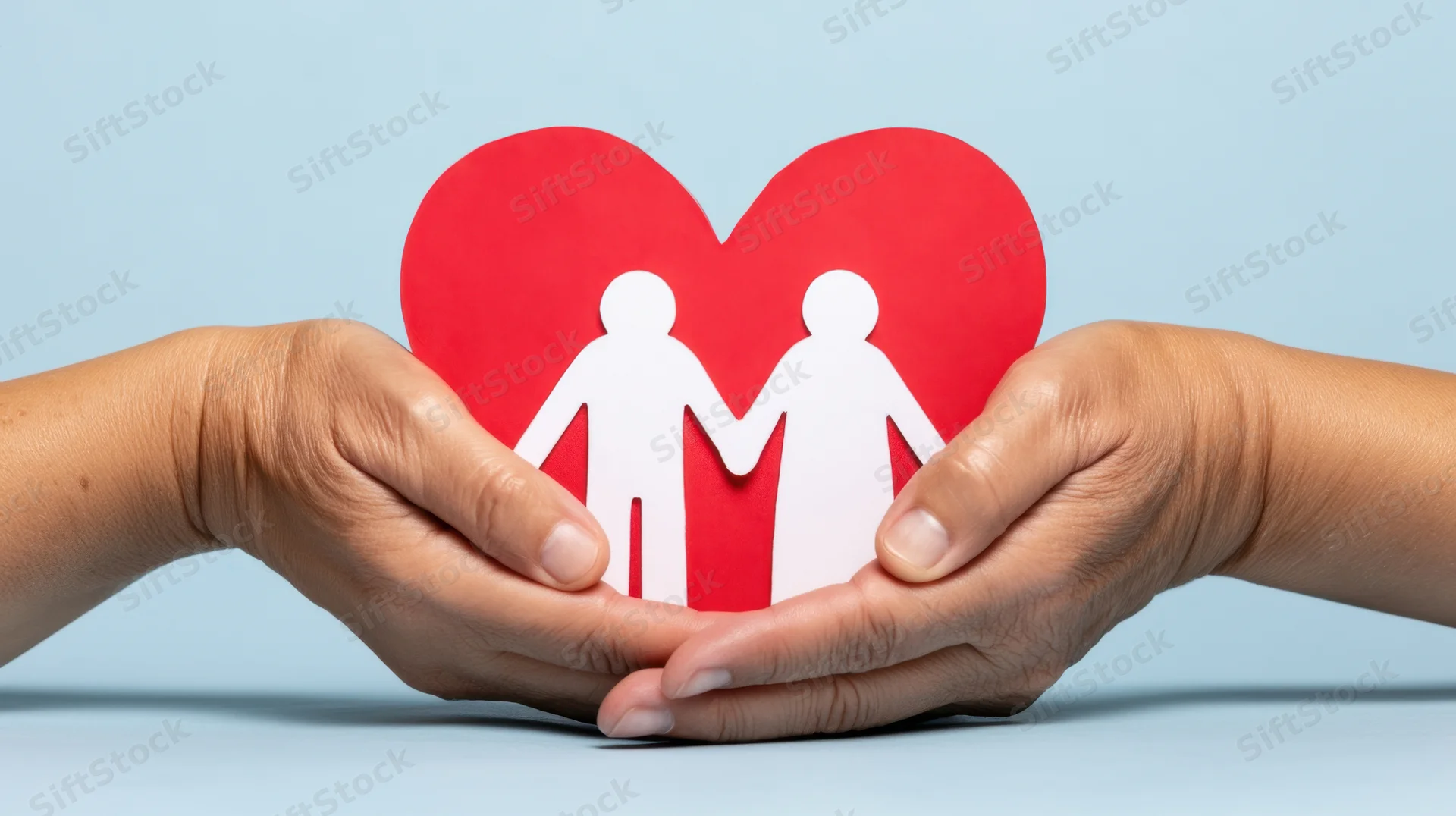 Hands holding a red paper heart with white family cutout against blue background