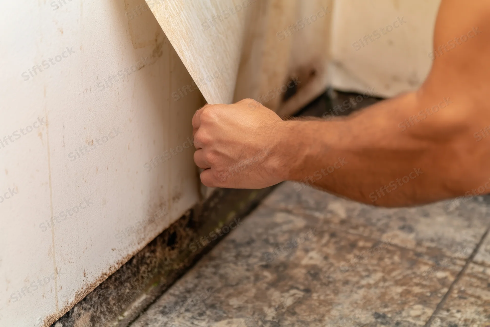 Man’s arm and hand gripping a wall panel during home renovation work
