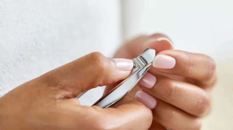 Woman trimming her nails with metal clippers at home