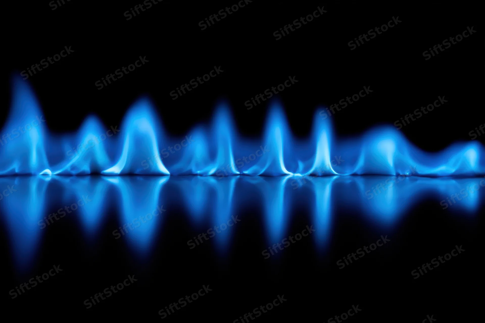 Blue flames burning along a reflective surface against a black background