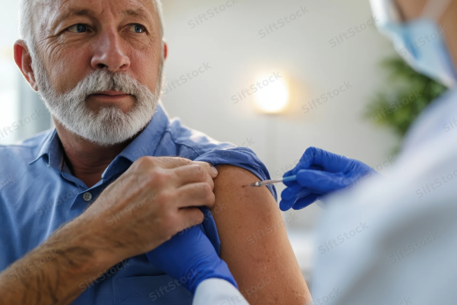 Senior man receiving injection in arm at clinic