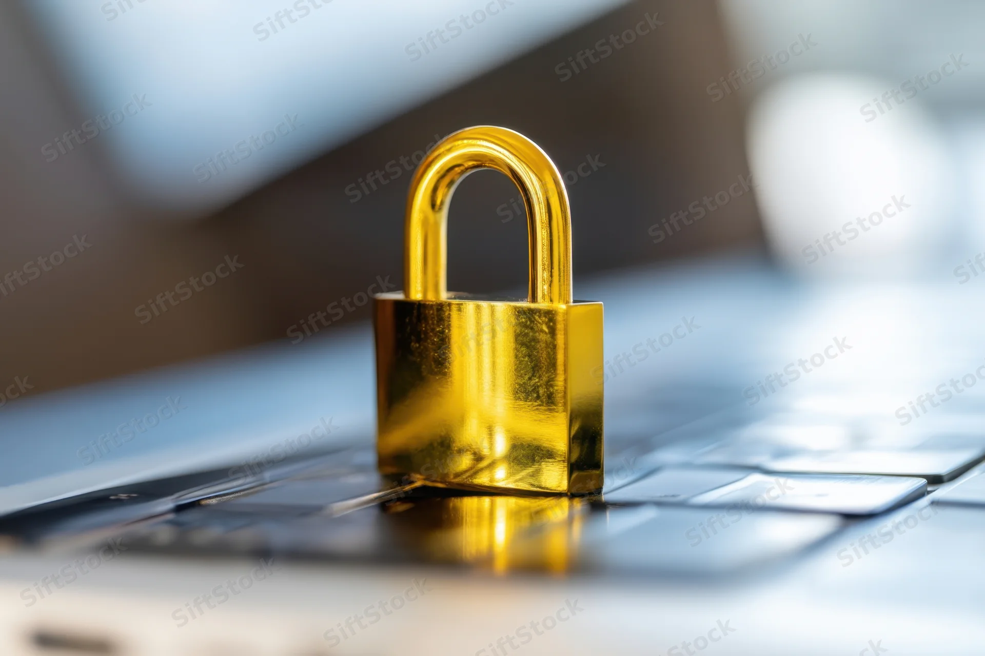 Golden padlock resting on laptop keyboard in office setting
